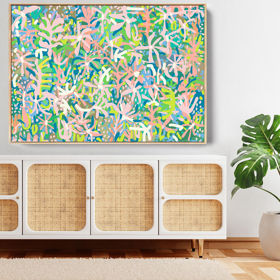 Colorful abstract painting on a wall above a wicker cabinet with a plant to the right.